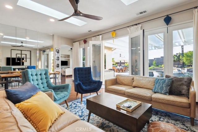 living room with hardwood / wood-style floors, ceiling fan, and a skylight