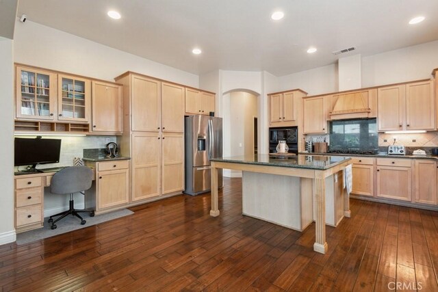 kitchen with a kitchen island, a kitchen bar, stainless steel fridge with ice dispenser, and dark wood-type flooring