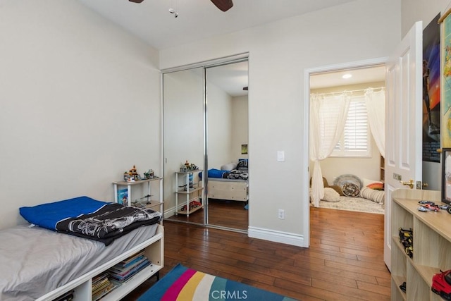 bedroom with ceiling fan, dark wood-type flooring, and a closet