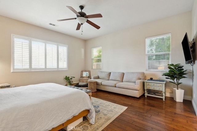 bedroom featuring ceiling fan, dark hardwood / wood-style flooring, and multiple windows