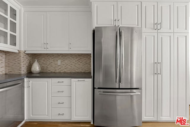 kitchen featuring appliances with stainless steel finishes, decorative backsplash, light hardwood / wood-style flooring, and white cabinets