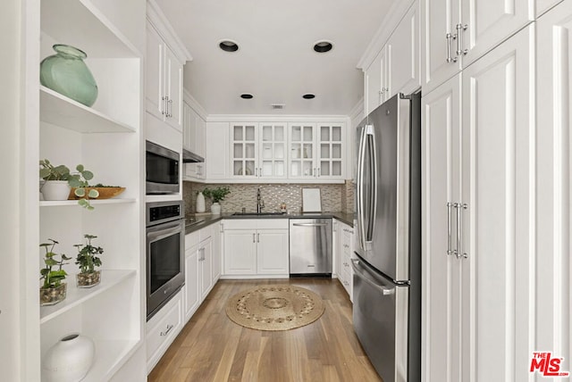 kitchen with tasteful backsplash, light hardwood / wood-style flooring, sink, appliances with stainless steel finishes, and white cabinetry