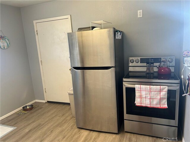 kitchen with appliances with stainless steel finishes and light hardwood / wood-style flooring