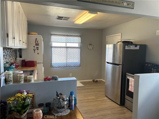 kitchen featuring tasteful backsplash, electric range oven, light hardwood / wood-style flooring, stainless steel refrigerator, and white cabinets