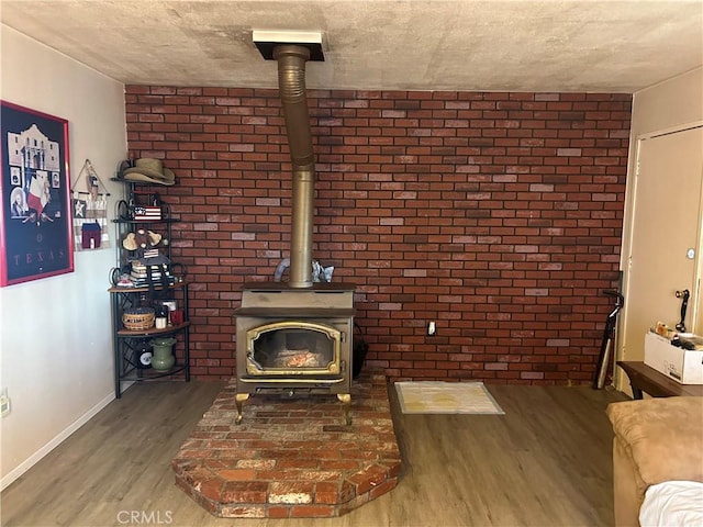 living room with hardwood / wood-style flooring, brick wall, and a wood stove