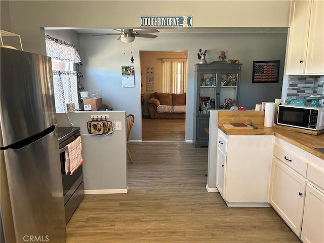 kitchen featuring appliances with stainless steel finishes, tasteful backsplash, white cabinetry, ceiling fan, and light hardwood / wood-style flooring