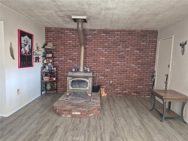 63737 Gibson Rd, Joshua Tree, CA 92252 - unfurnished living room with a wood stove, wood finished floors, and brick wall