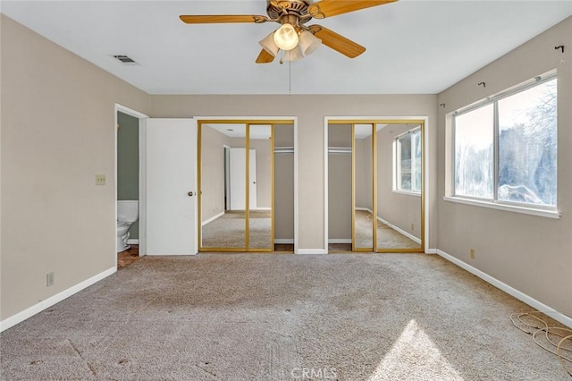 unfurnished bedroom with carpet floors, two closets, visible vents, and baseboards