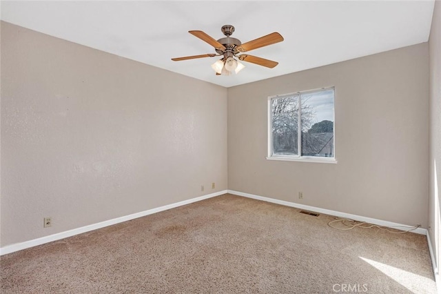 carpeted empty room featuring baseboards, visible vents, and ceiling fan