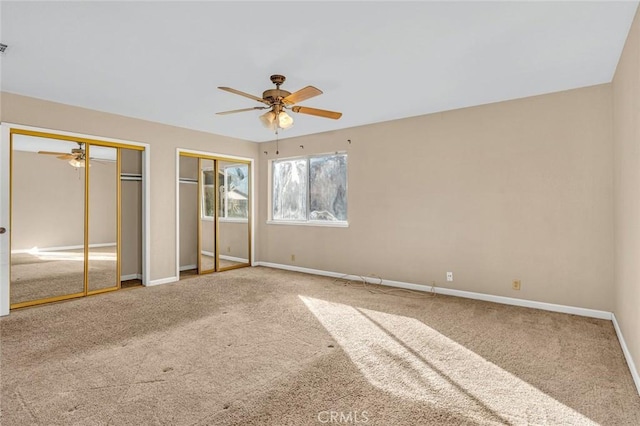 unfurnished bedroom featuring ceiling fan, carpet flooring, two closets, and baseboards