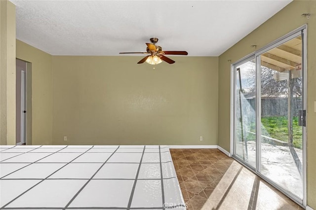 unfurnished room with ceiling fan, baseboards, and a textured ceiling