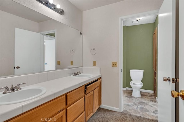 bathroom featuring double vanity, baseboards, toilet, and a sink