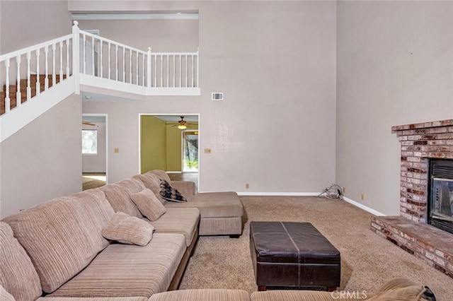 living room with visible vents, baseboards, light colored carpet, a high ceiling, and a fireplace