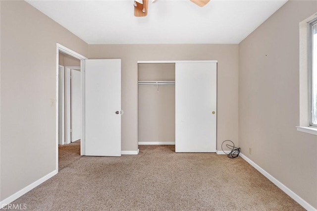 unfurnished bedroom with light carpet, a closet, a ceiling fan, and baseboards