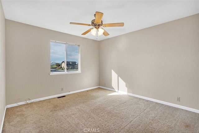 carpeted spare room with visible vents, ceiling fan, and baseboards