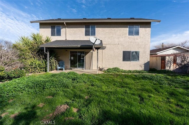 rear view of property featuring stucco siding, a lawn, and a patio