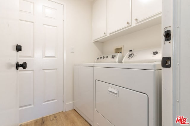 clothes washing area featuring cabinets, separate washer and dryer, and light hardwood / wood-style flooring