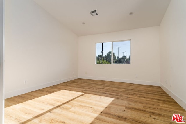 empty room featuring hardwood / wood-style floors and vaulted ceiling