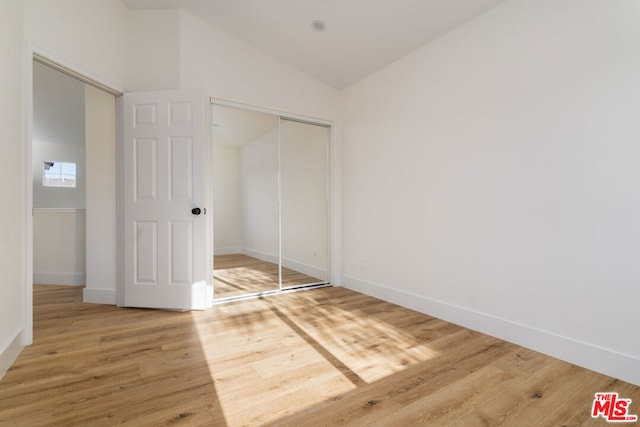 unfurnished bedroom featuring a closet, wood-type flooring, and lofted ceiling