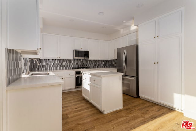 kitchen featuring white cabinetry, sink, stainless steel appliances, light hardwood / wood-style flooring, and a kitchen island