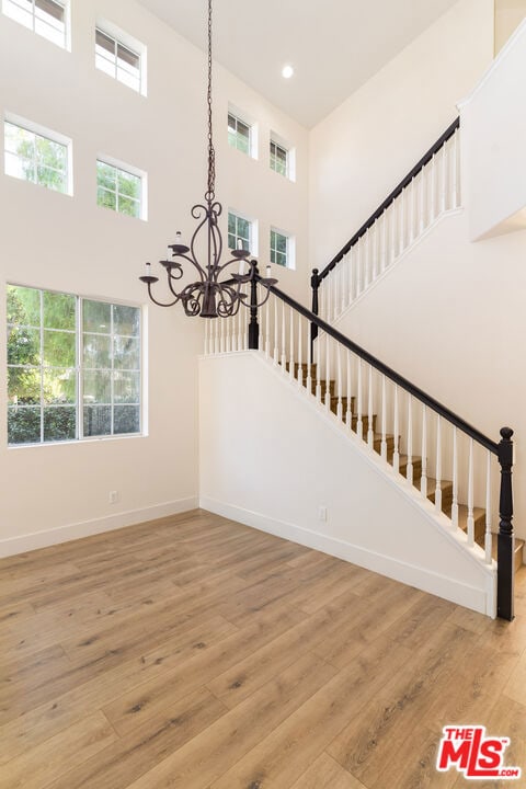 stairway with hardwood / wood-style flooring, a towering ceiling, and a chandelier