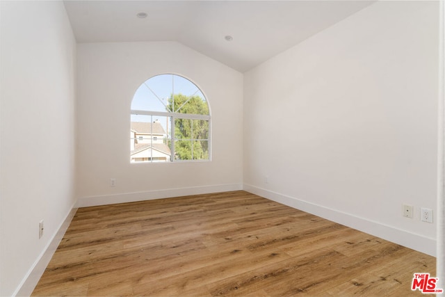 empty room with wood-type flooring and lofted ceiling