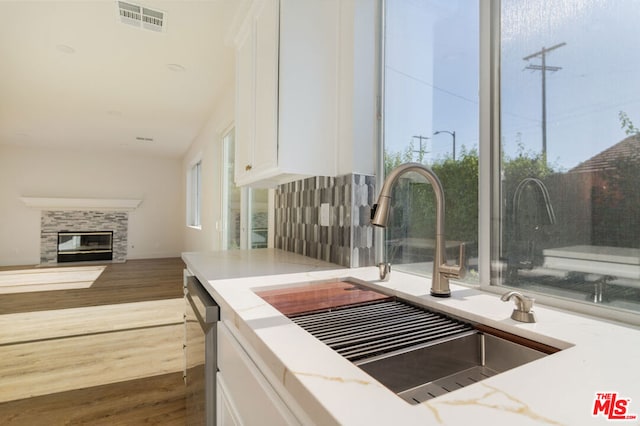 kitchen with a fireplace, dark hardwood / wood-style flooring, white cabinetry, and sink