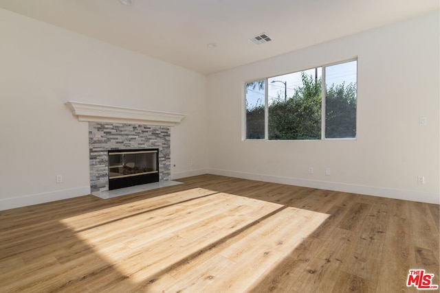 unfurnished living room featuring hardwood / wood-style floors and a tiled fireplace