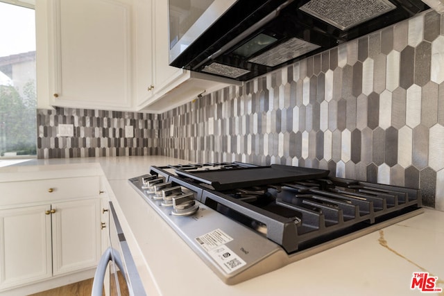 kitchen with white cabinetry, decorative backsplash, ventilation hood, and stainless steel gas cooktop