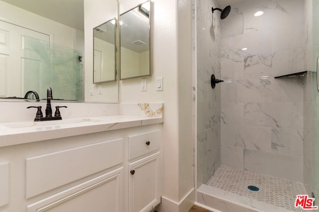 bathroom with a tile shower and vanity