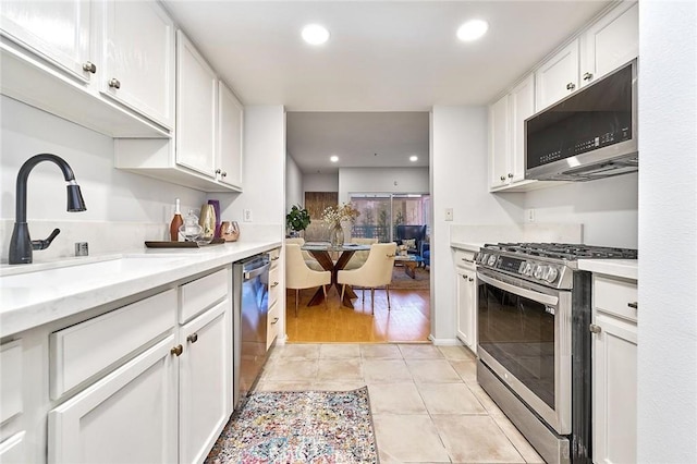 kitchen featuring appliances with stainless steel finishes, light hardwood / wood-style flooring, white cabinetry, and sink