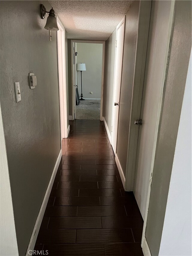 hall featuring a textured ceiling and dark hardwood / wood-style flooring