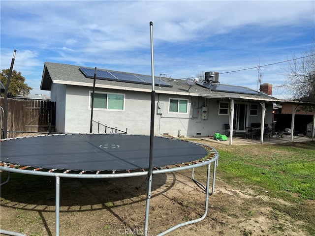 back of property with a patio, solar panels, central AC unit, and a trampoline