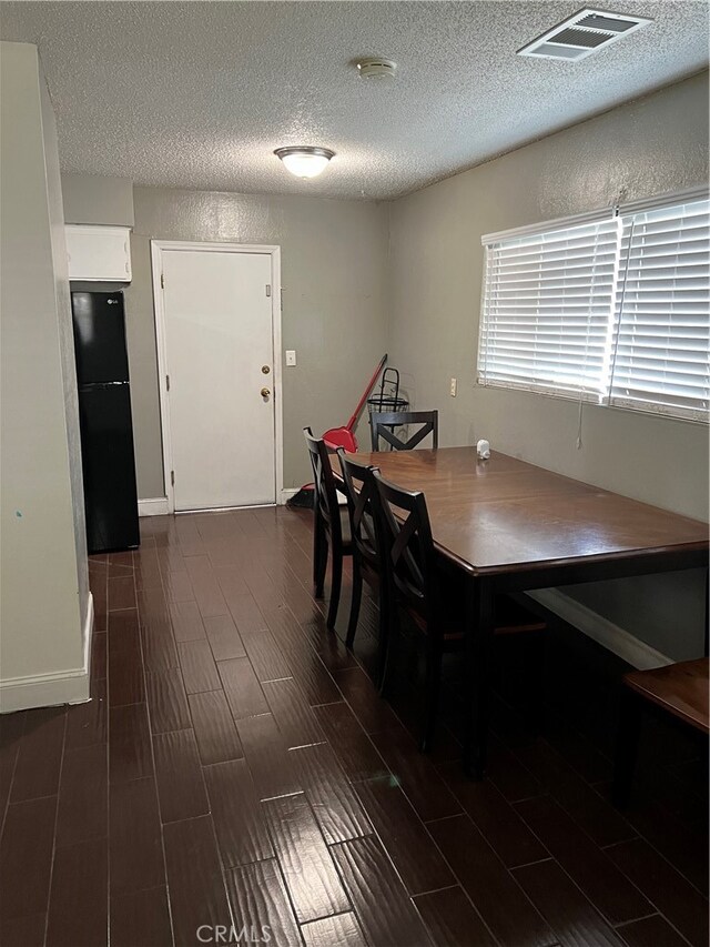 dining room featuring a textured ceiling and dark hardwood / wood-style floors