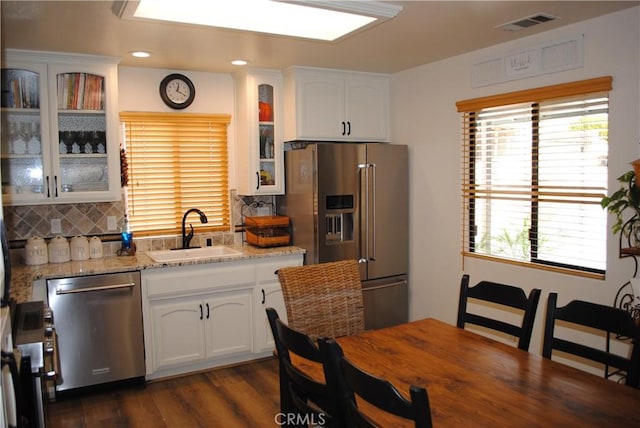 kitchen with white cabinets, decorative backsplash, sink, and stainless steel appliances