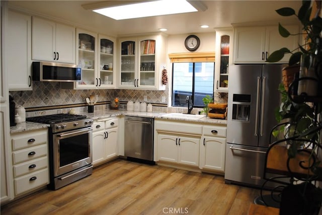 kitchen with white cabinets, appliances with stainless steel finishes, light hardwood / wood-style flooring, and sink