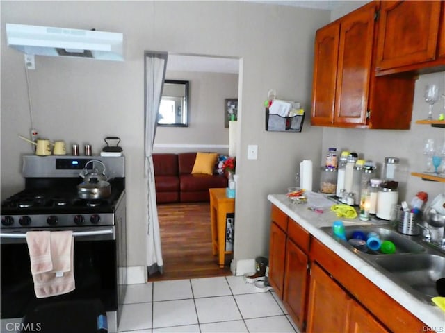 kitchen featuring sink, gas stove, light tile patterned flooring, and ventilation hood