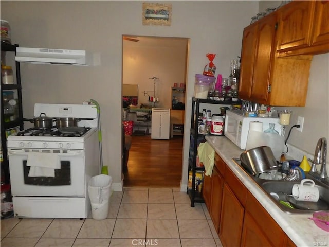 kitchen featuring sink, exhaust hood, light tile patterned flooring, and white appliances