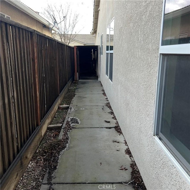 view of side of home featuring fence and stucco siding