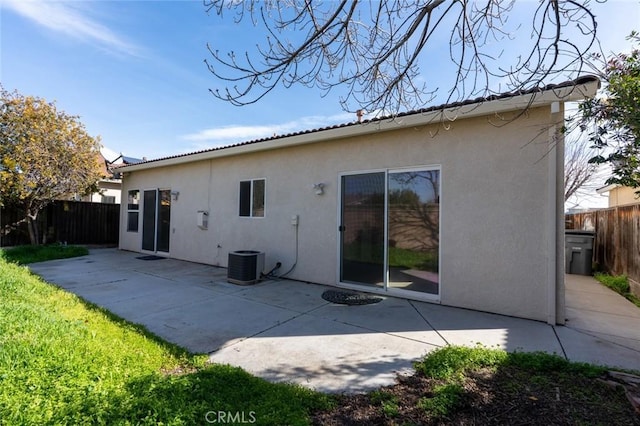 rear view of house with a patio area, fence, central AC, and stucco siding