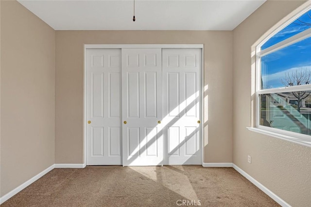 unfurnished bedroom featuring a closet, carpet flooring, and baseboards