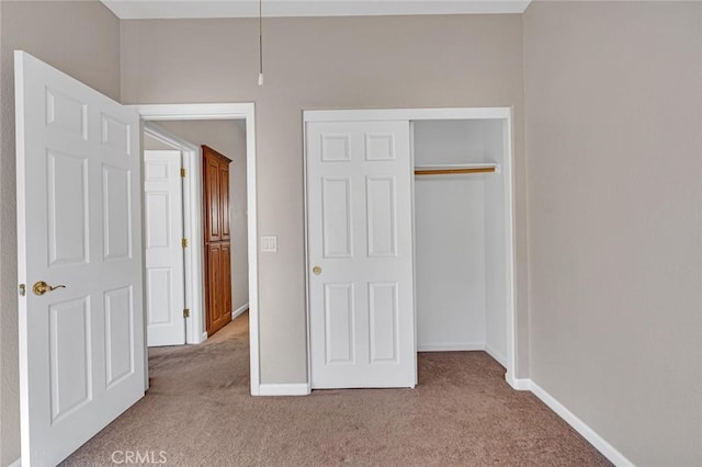 unfurnished bedroom with carpet floors, a closet, and baseboards