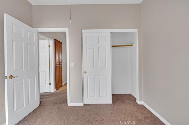 unfurnished bedroom with a closet, baseboards, and carpet flooring