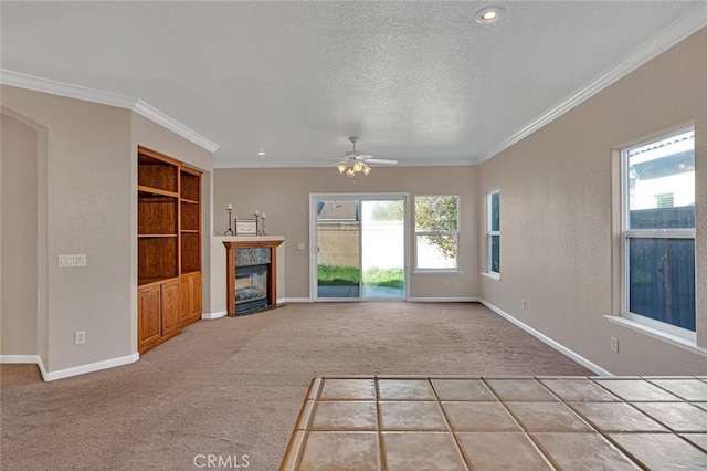 unfurnished living room with a textured ceiling, built in shelves, a fireplace, ornamental molding, and carpet