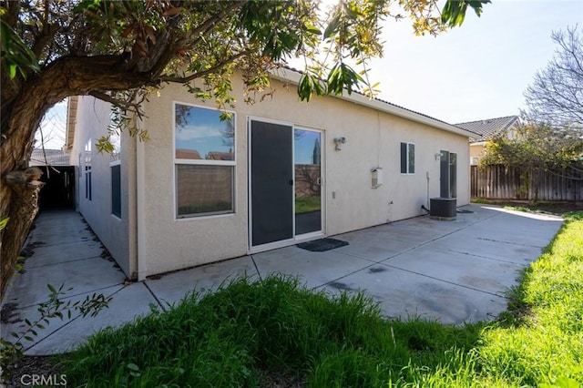 rear view of house with a patio, central AC, fence, and stucco siding