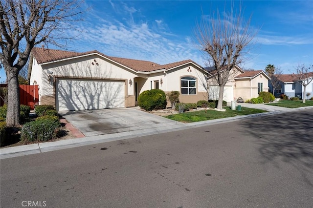 view of front of house featuring a tile roof, driveway, an attached garage, and stucco siding