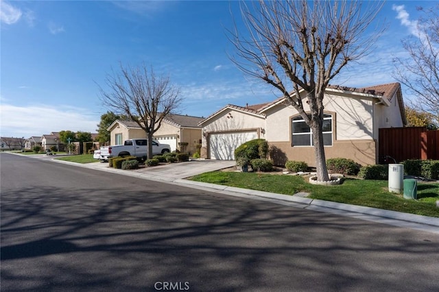 view of front of property with an attached garage, a residential view, fence, and stucco siding