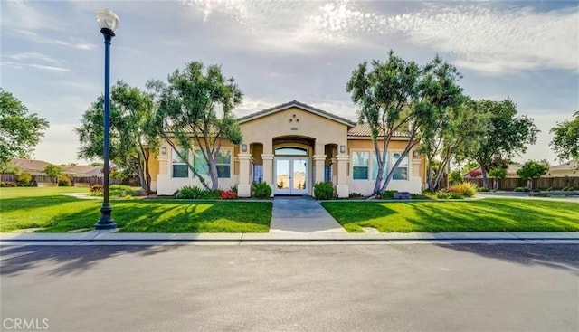 mediterranean / spanish home featuring french doors, a front yard, and stucco siding