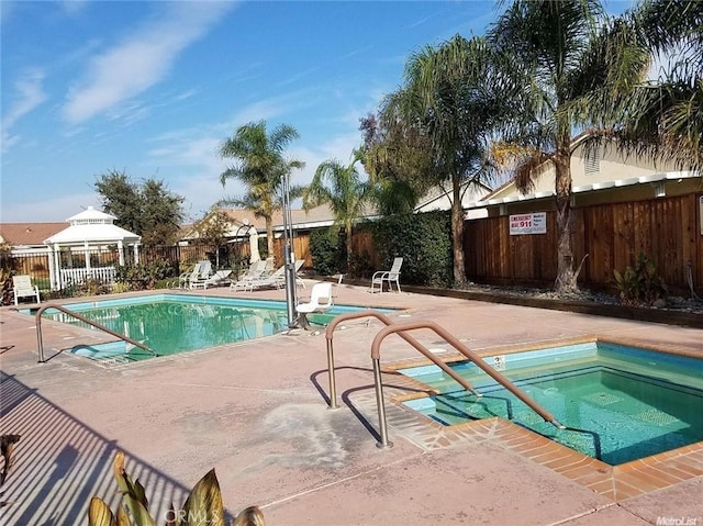 pool featuring a patio area, fence, and a hot tub