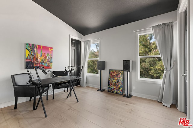 home office featuring a textured ceiling, lofted ceiling, and light wood-type flooring